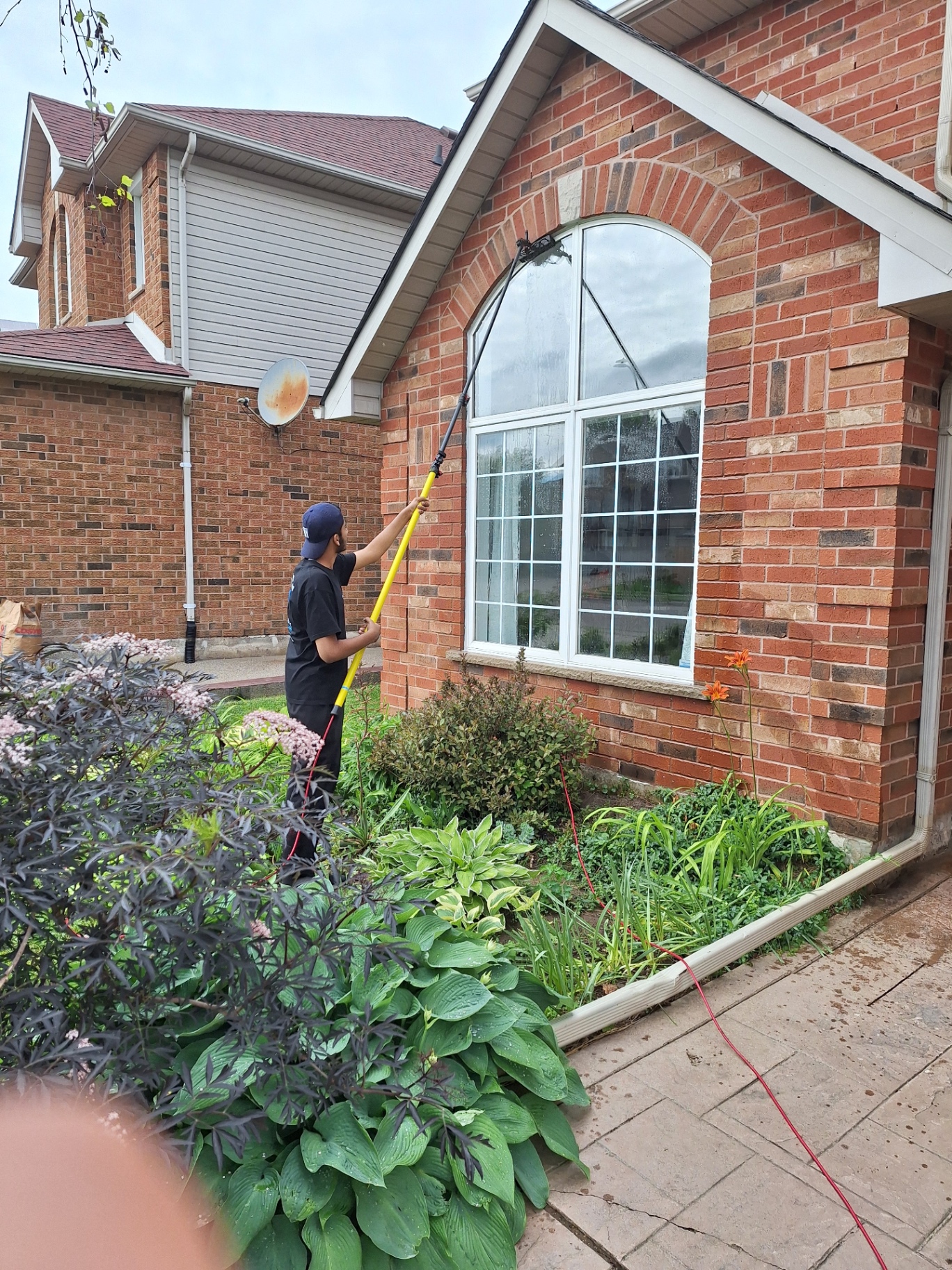 Crystal Works technician cleaning arched exterior window with water-fed pole